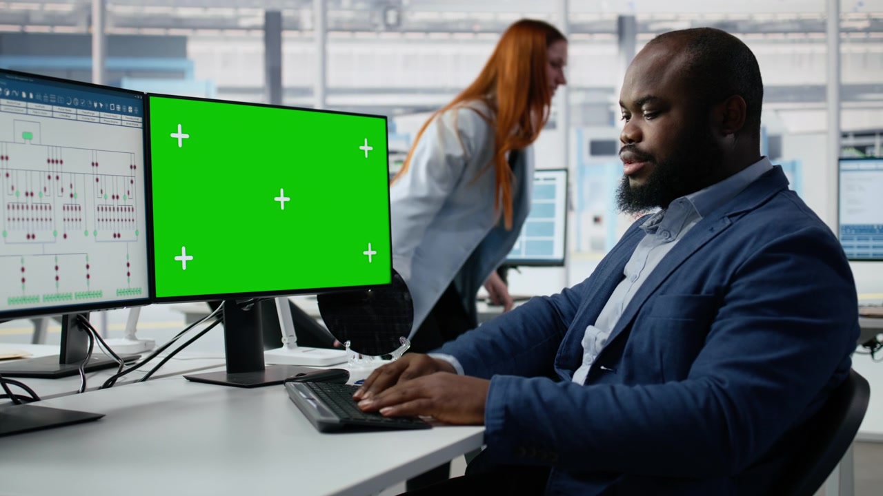 Professionel afroamerikansk mand arbejder ved computer med grøn skærm