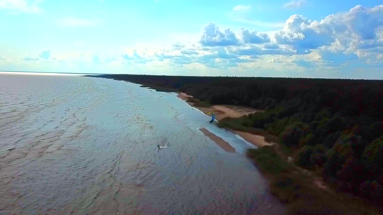 surfista de cometas golpeando las olas con cielos azules y nubes