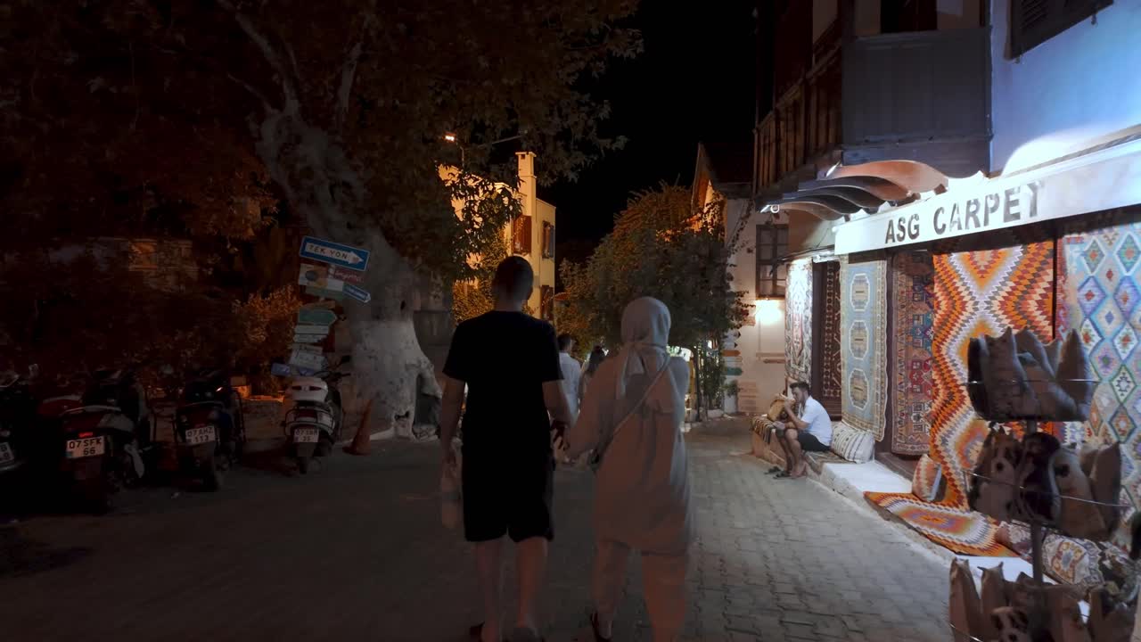 A night walk through Kaş's old town, showcasing charming shops and vibrant street life under the city lights.