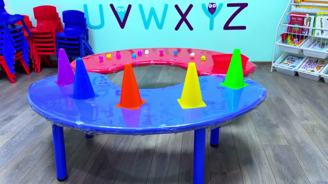 Bright preschool setup with colorful cones on a learning table in front of alphabet-themed decor. Ideal for early education, training, or child development content. Captured in sharp 4K quality.