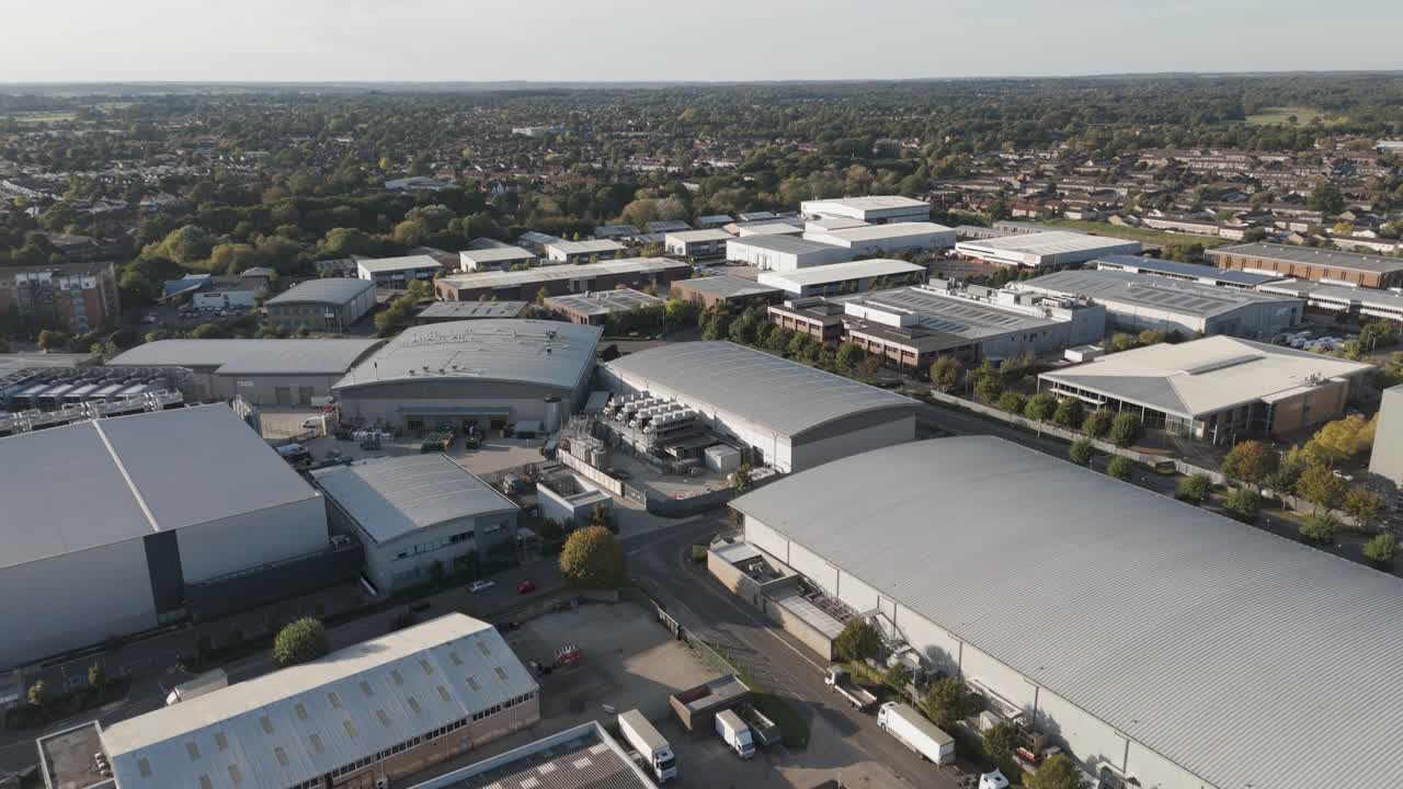Rising aerial view capturing Slough trading estate bathed in warm golden hour light, showcasing industrial architecture and commercial infrastructure
