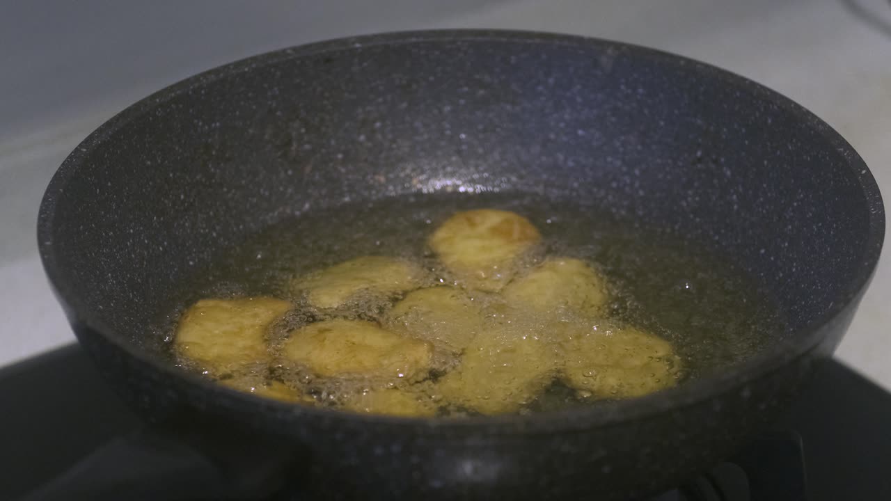 Nærbillede af nuggets, der friteres i en køkkenwok fyldt med vegetabilsk olie
