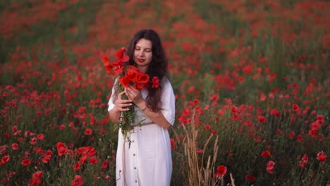 Allgemeiner-Plan:-Wunderschönes-Dunkelhaariges-Mädchen-Auf-Einem-Feld-Mit-Wildblumen-Und-Roten-Mohnblumen,-Trägt-Einen-Hut-Und-Ein-Kleid,-Hält-Einen-Blumenstrauß-Und-Lächelt-Neben-Weizenhalmen