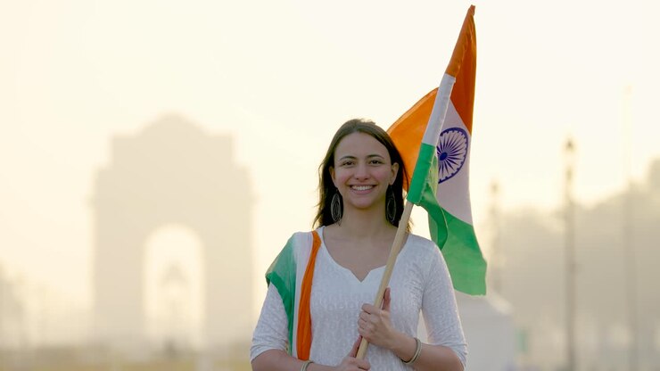 orgullosa niña india sosteniendo la bandera india en un traje tradicional indio y un chunni de tres colores en la puerta de la india en delhi