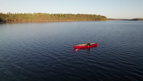 Cool-360-aerial-shot-of-a-canoeist-paddling-a-remote-wilderness-lake,-4K