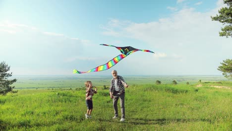 caucasian senior man with his grandson in the park while they are flying a kite on a sunny day