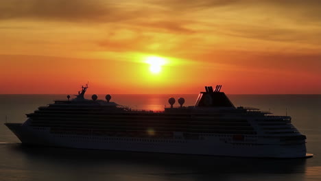 a large cruise ship sailing on the ocean during a vibrant sunset
