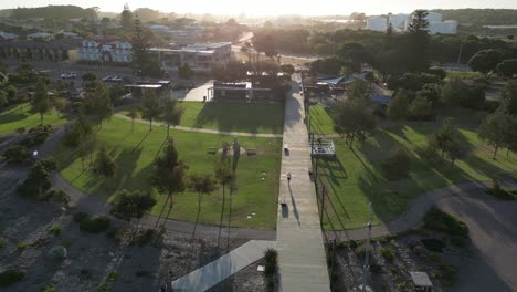 tomada de seguimiento aéreo de una persona corriendo por el camino en el parque durante la puesta de sol dorada