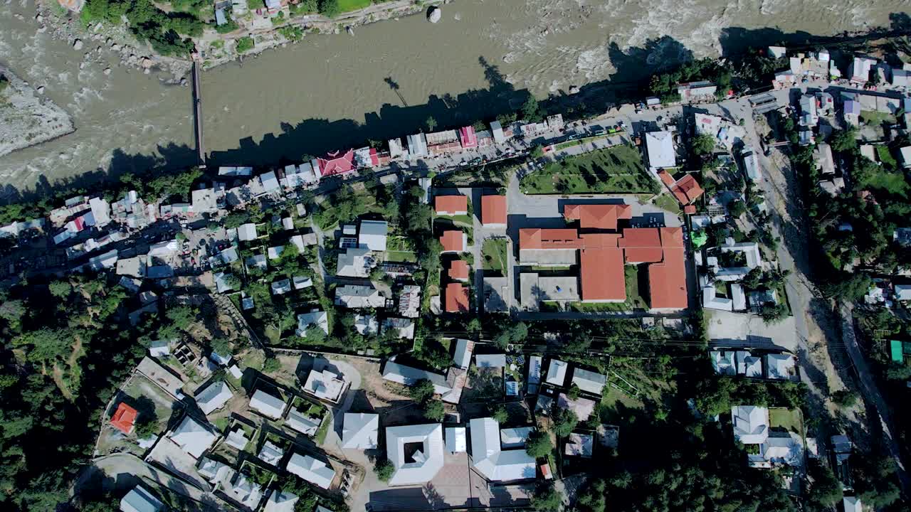 Top-down aerial shot of Athmuqam Neelum Valley - Aerial shot of buildings, houses, river, and green town of Kashmir