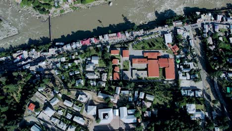 top-down aerial shot of athmuqam neelum valley - aerial shot of buildings, houses, river, and green town of kashmir