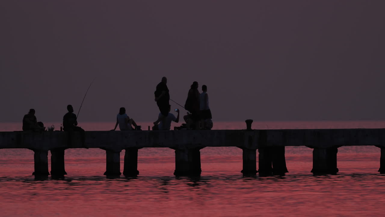 Family Silhouettes Fishing at Sunset Pier