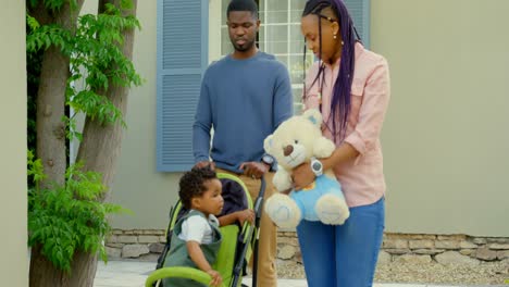 Vista-Frontal-Joven-Familia-Negra-Caminando-Sobre-El-Pavimento-En-El-Patio-Trasero-De-Su-Casa-4k