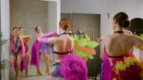 three latin dancers doing rehearsals of the cabaret dance in front of a mirror