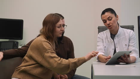 médico mostrando la imagen en el dispositivo a una pareja