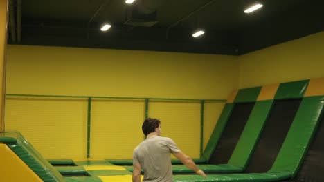 young attractive brunete male springs over yellow barrier at professional trampoline. youth, sport, gymnastics.