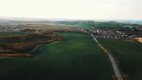 beautiful green landscape at golden hour. the road where the car passes. hilly landscape full of lights and shadows. shot of a drone. meadows and forests from a bird's eye view. czech republic, south