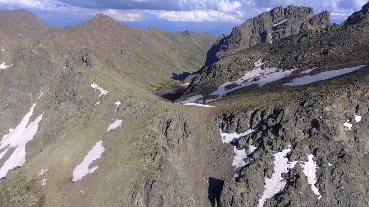 雪と雲に覆われた険しい山々の空撮。