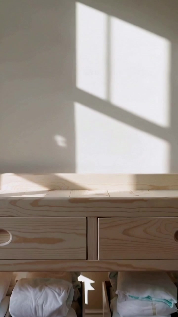Vertical video: Camera panning over pine cabinet at home to reveal drawers and boxes with linens