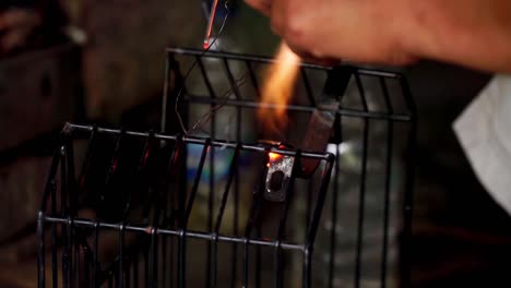 Close-up-of-person-welding-a-cage-while-a-lot-of-sparks-fly-in-local-workshop