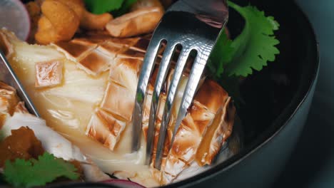 Close-up-of-cutting-with-knife-and-fork-through-a-piece-of-hot-grilled-camambert-cheese