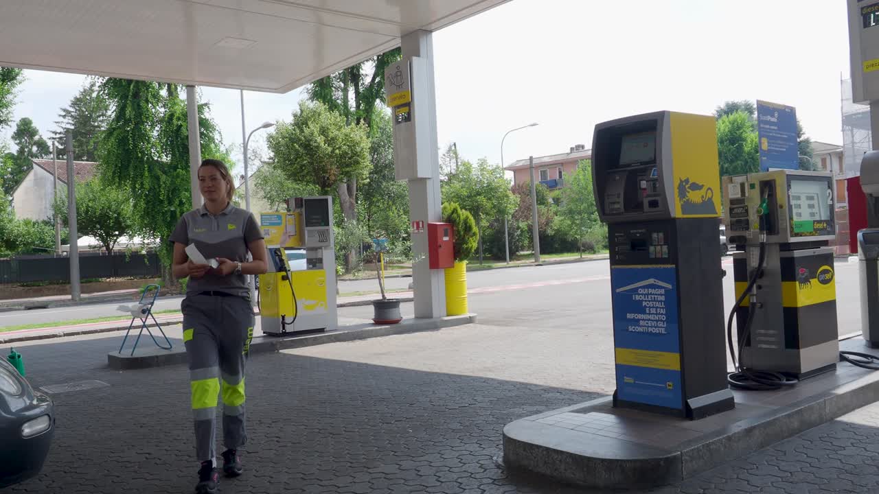 Man and woman in gas station uniforms process credit card payment for fuel, using modern wireless technology for quick, convenient service in an urban setting