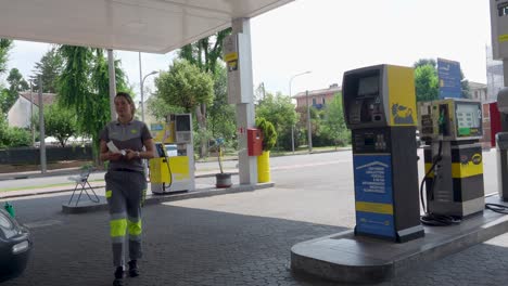 man and woman in gas station uniforms process credit card payment for fuel, using modern wireless technology for quick, convenient service in an urban setting