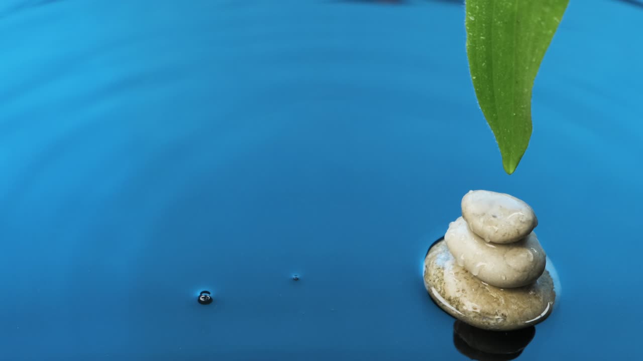 Pyramid, leaf and droplet falling in blue water. Panorama.