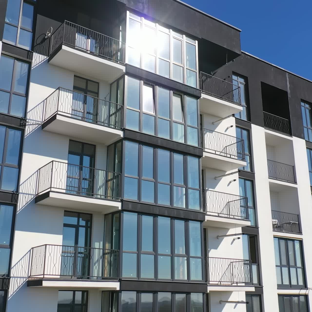 Beautiful design of multistorey building. New apartment with balconies against blue sky. Exterior of residential building