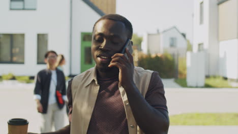 Black-Man-Walking-on-Street,-Drinking-Coffee-and-Speaking-on-Phone