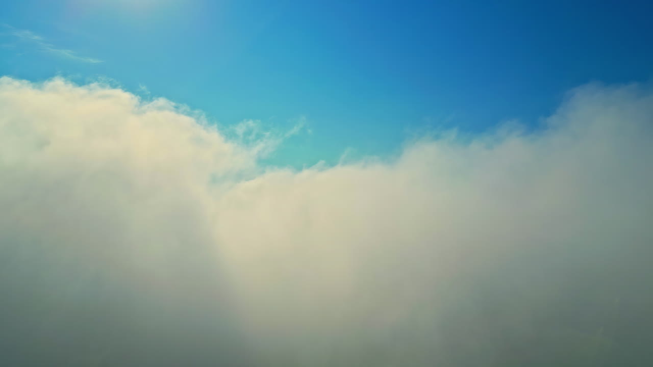 Flying through clouds towards the blue heavens - push forward view