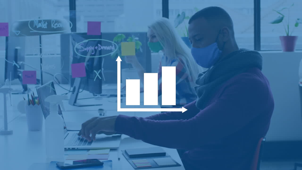 Animation of bar graph icon against african american man wearing face mask using laptop at office
