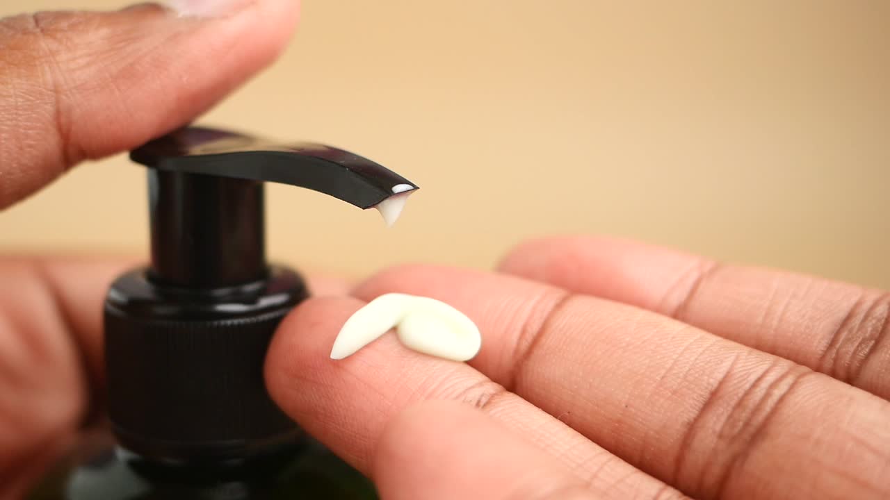 Primer plano de un dosificador de loción vertiendo producto en una mano
