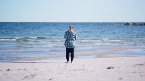 Girl-standing-on-the-beach-taking-photos-of-the-ocean