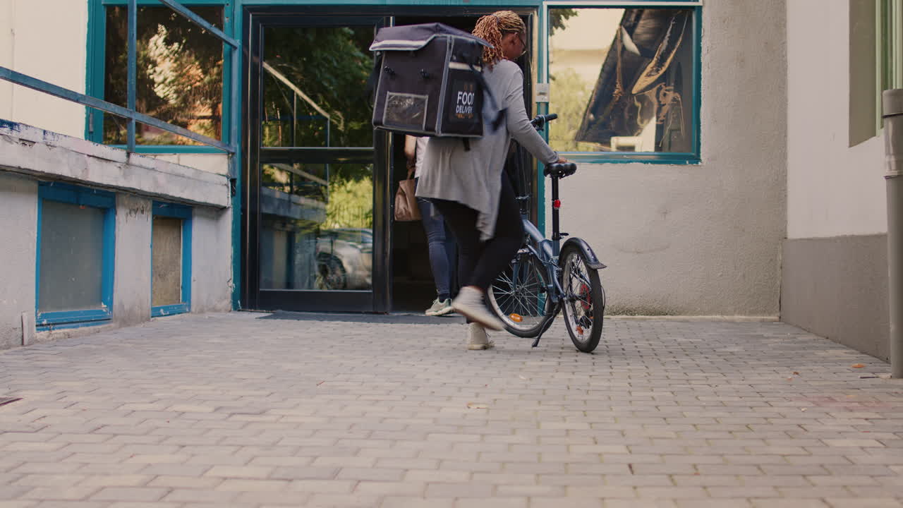 Food delivery person with bicycle entering a building