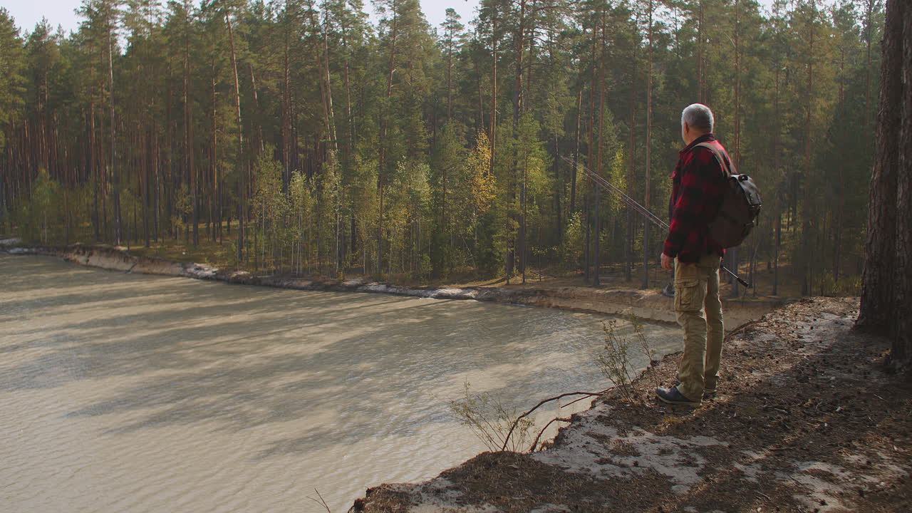 экологический туризм в лесу с озером человек смотрит на водохранилище с вершины холма с соснами расслабиться на природе