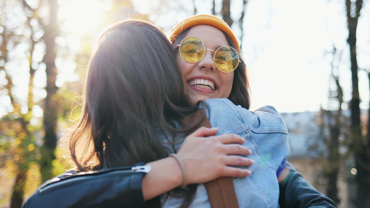 Close-up view of happy hipster group of friends greeting and hugging in the park in autumn