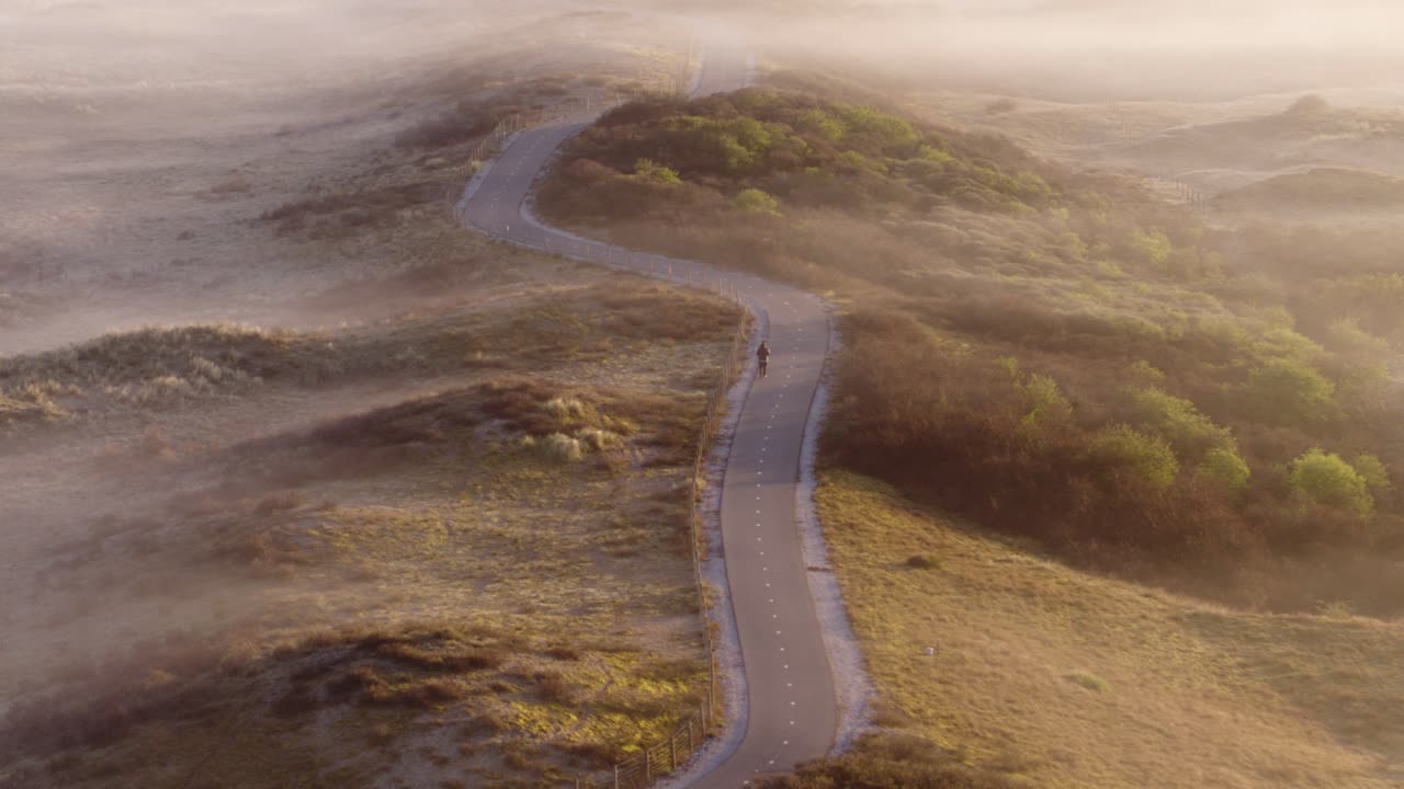 camino para bicicletas de la mañana con niebla a través de las dunas