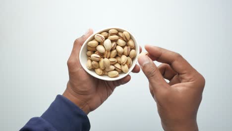 person holding a bowl of pistachios