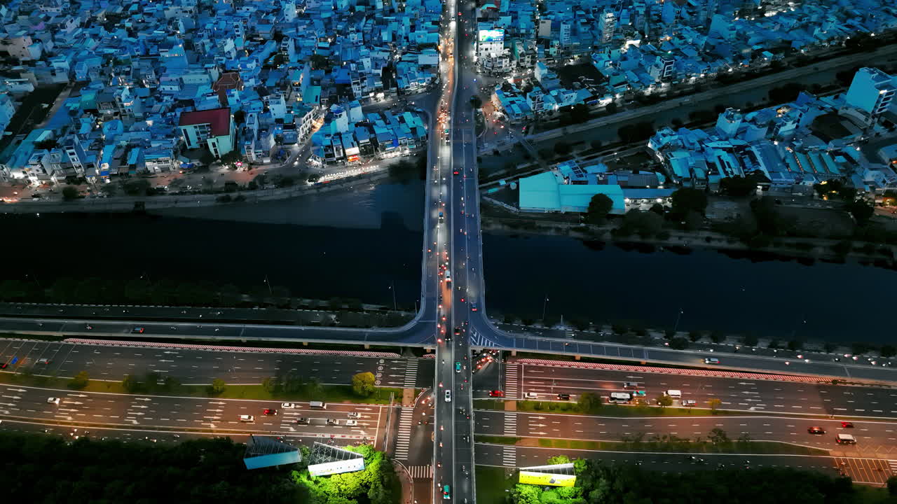 Aerial view of a busy highway junction in an Asian city, with layered roads and flowing traffic. Skyscrapers and urban landscapes surround, showcasing dynamic infrastructure and city life