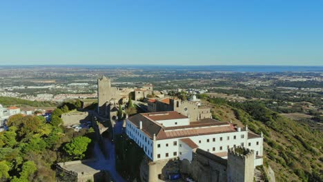 Drone-shot-descending-by-the-castle-on-the-hill-in-Palmela,-Portugal