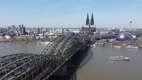 Toma-Aérea-De-Establecimiento-Famosa-Catedral-De-Colonia---Dom-Vista-Panorámica-Del-Centro-De-La-Ciudad-Y-El-Puente-Ferroviario-Hohenzollern-Sobre-El-Río-Rin