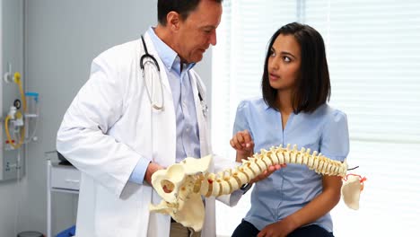 fisioterapeuta explicando el modelo de la columna vertebral al paciente