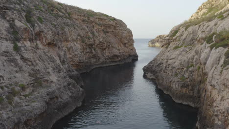 Aerial-shot-through-the-rocky-sea-valley-of-Wied-il-Għasri,Malta