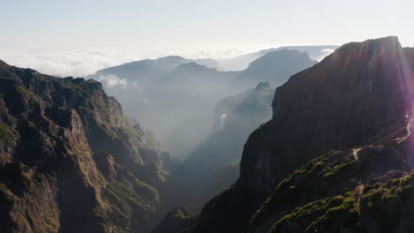 Drone-shot-of-Madeira-with-cliffs,-mountains-and-a-valley-with-clouds-at-sunset