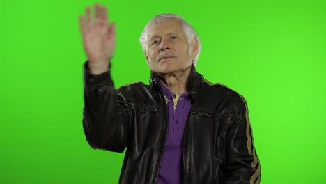 anciano abuelo caucásico rocker y motociclista hombre agita sus manos, saluda