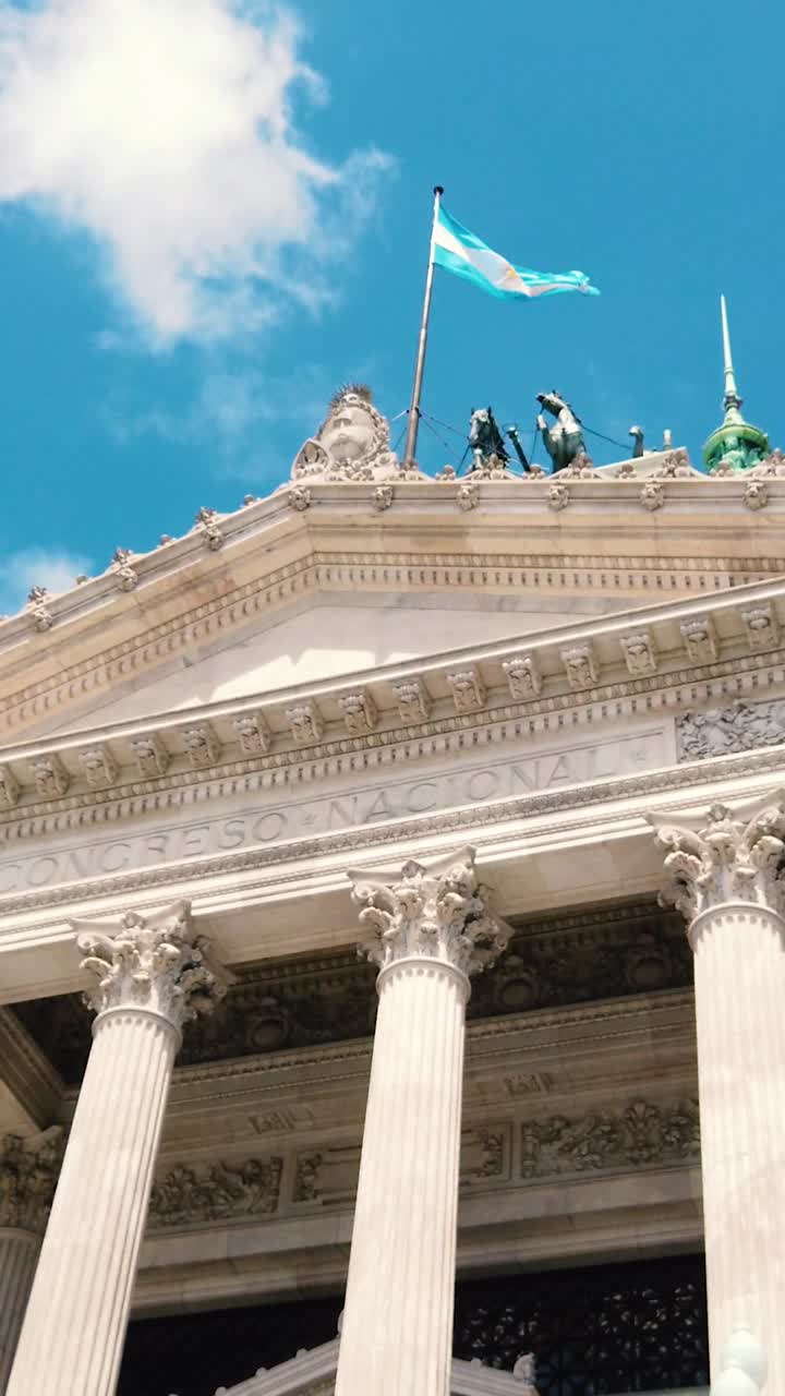 Argentine flag waves in blue daylight skyline with National Congress, vertical view at Buenos Aires city, Historical architecture