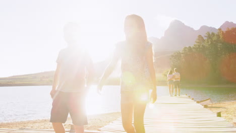 kids admiring scenery by lake while parents stand on a jetty