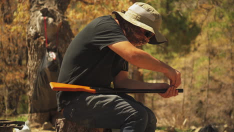 A-man-sits-and-reloads-his-bb-gun-while-hunting-for-sport-in-a-forest