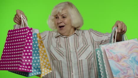 abuela mayor levantando bolsas de compras, celebrando, satisfecha con la compra, descuento. llave de croma
