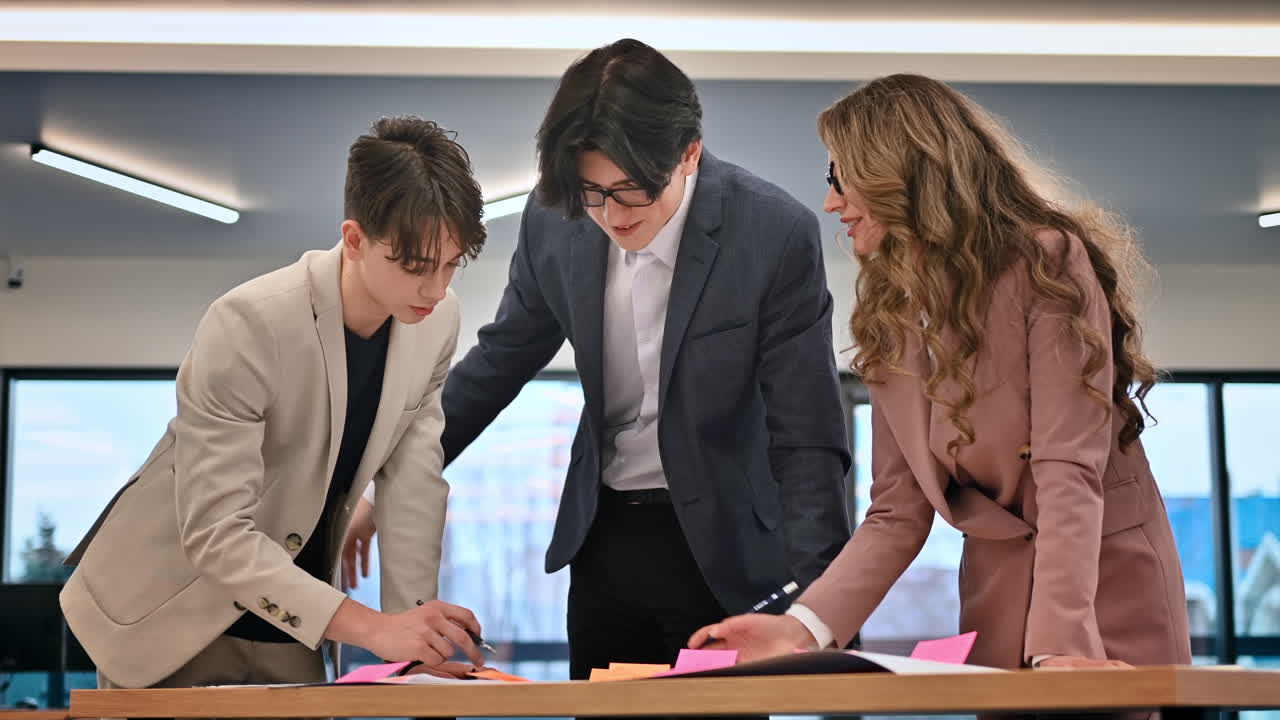 Riunione di lavoro in ufficio, team leader donna e due giovani dipendenti che discutono di affari usando dei documenti. Rallentatore
